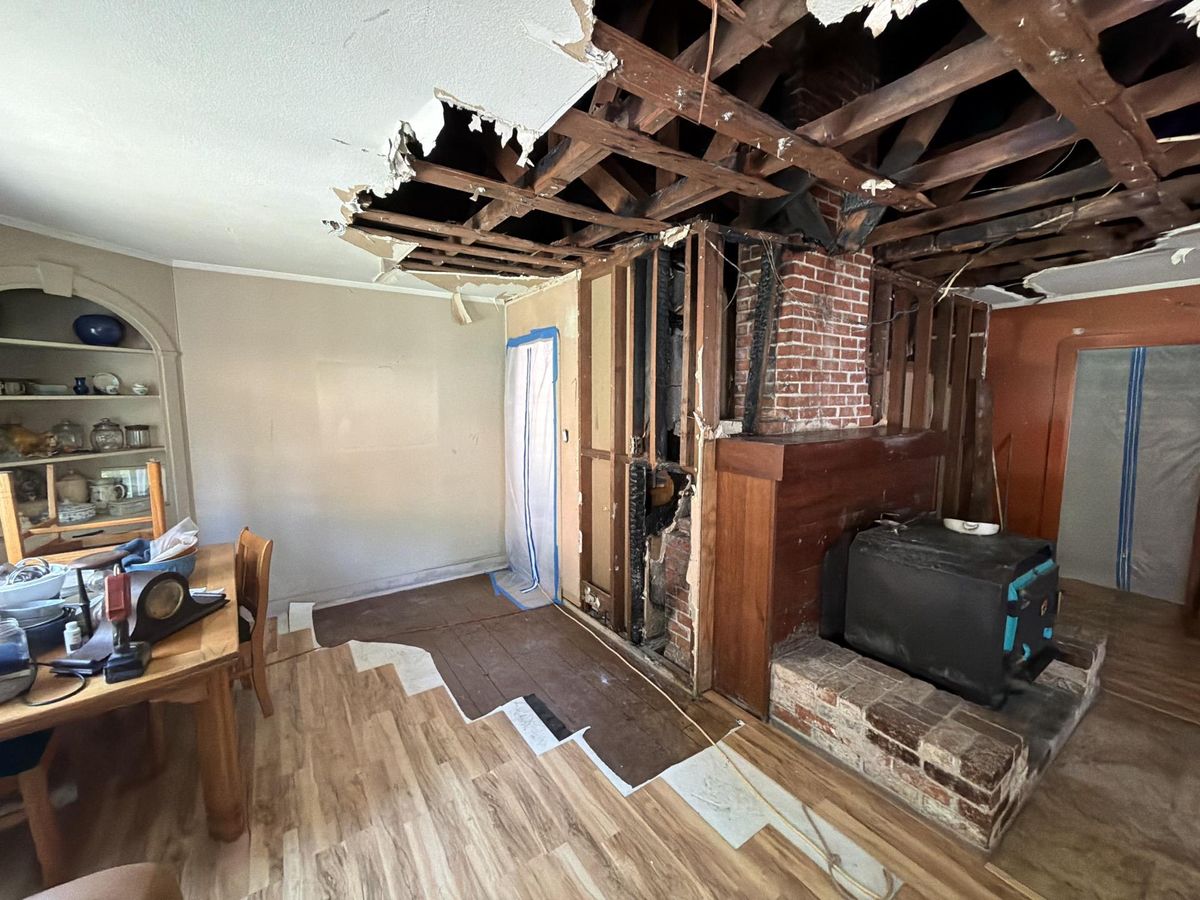 Fire damage cleanup in progress after a chimney fire — charred framing exposed, containment in place, by North Coast Restoration